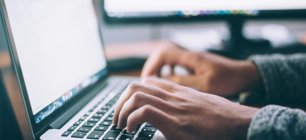 man researching driving schools on laptop